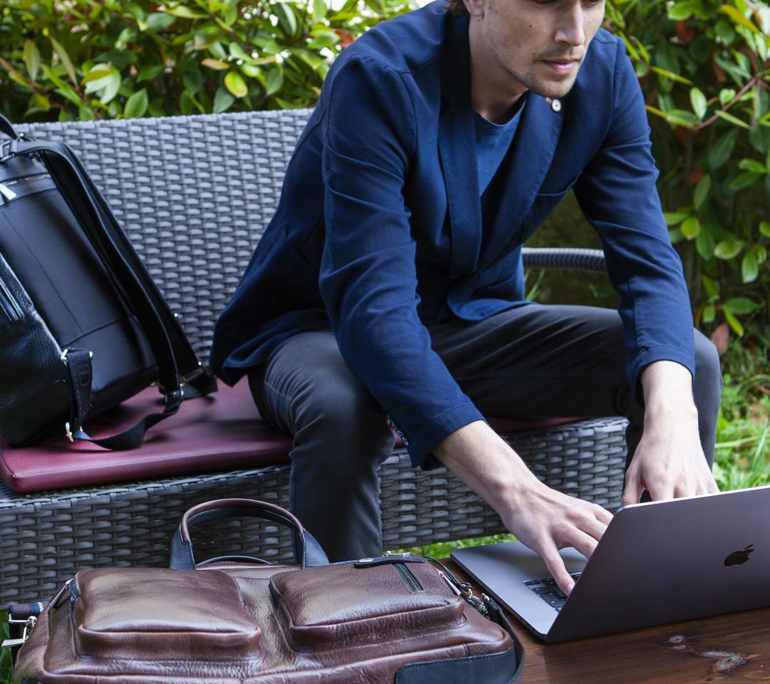 Ragazzo che lavora al computer con accanto una Laptop bag Chiarugi Firenze della linea Old-Tuscany.