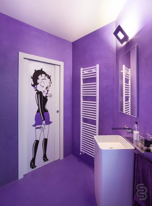 bagno viola con adesivo Murale Betty Boop sulla porta bianca.